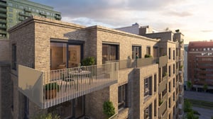 Modern lägenhetsbyggnad med fasad av tegel och stora balkonger, omgiven av flerbostadshus och grönska under en ljus himmel
