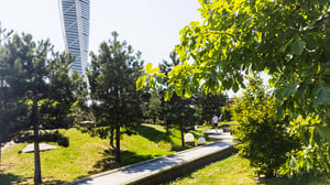 Grön parkmiljö i Malmö med promenadstig, träd och hög modern byggnad i bakgrunden