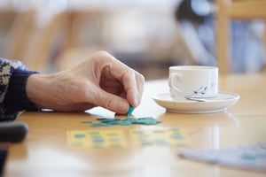 Närbild av en hand som placerar en spelbricka på ett bord bredvid en kaffekopp