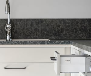 Kök med vit diskho, kromad blandare och utdragen låda i modern lägenhet