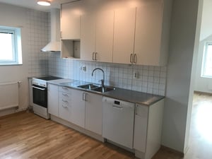 Köksinredning i vitt med spis och diskmaskin