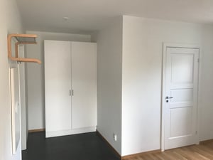 Hall med vita väggar, klinker innanför entrédörr och garderober i vitt