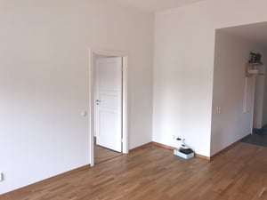 Omöblerat allrum med vita väggar och ekgolv