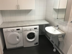 Badrum med vit kakel med tvättmaskin och torktumlare