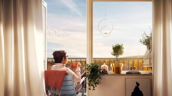 Kvinna på balkong med kopp i handen