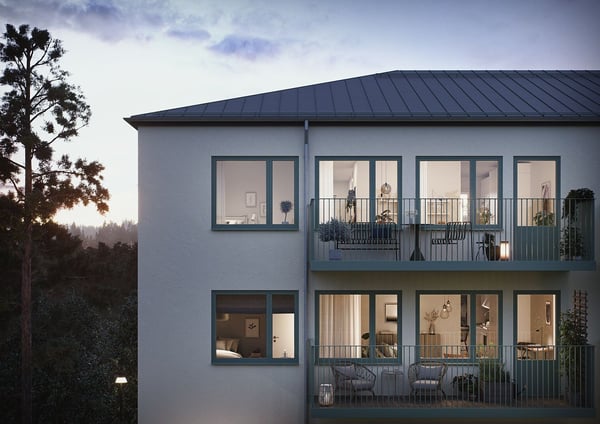 Flerfamiljshus i modern design med vita fasader, stora fönster och balkonger, omgiven av träd och natur i skymningsljus