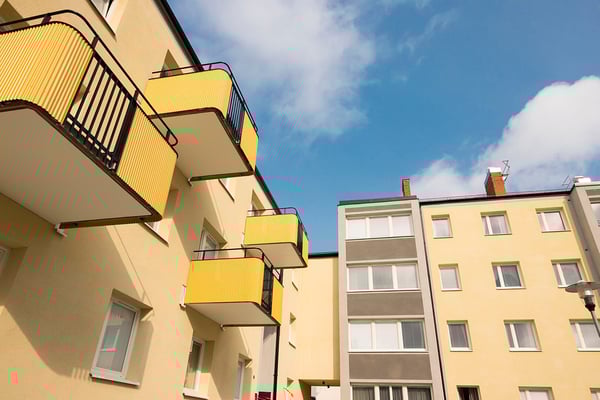 Gula flerfamiljshus med balkonger och blå himmel i bakgrunden