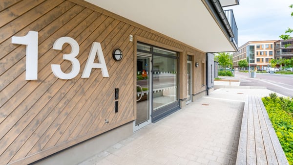 Entré till flerbostadshus med träfasad och husnummer 13A