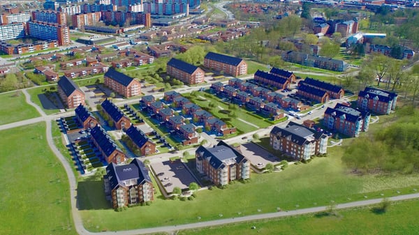 Flygvy över bostadsområde med flerbostadshus, radhus och grönområden