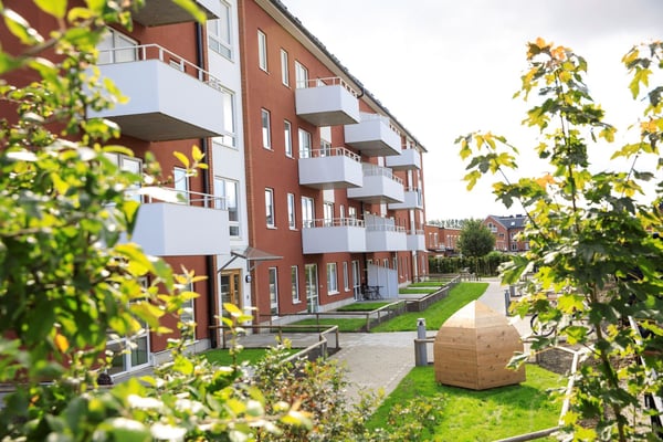 Rött flerbostadshus med balkonger och grön innergård