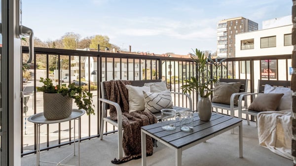 Balkong med soffgrupp, soffbord och utsikt över bostadshus