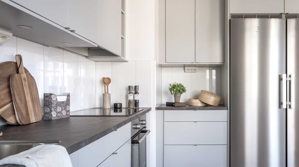 Kök med ljusa skåp, mörk bänkskiva och rostfri kyl