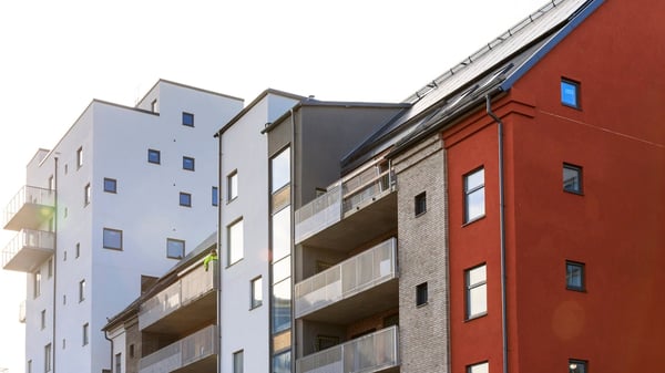Flerbostadshus med vita, grå och röda fasader samt balkonger