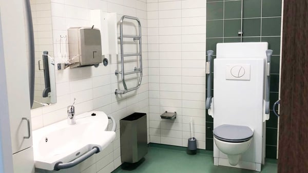 Tillgänglighetsanpassat badrum med handfat, toalett, stödhandtag och skötbord
