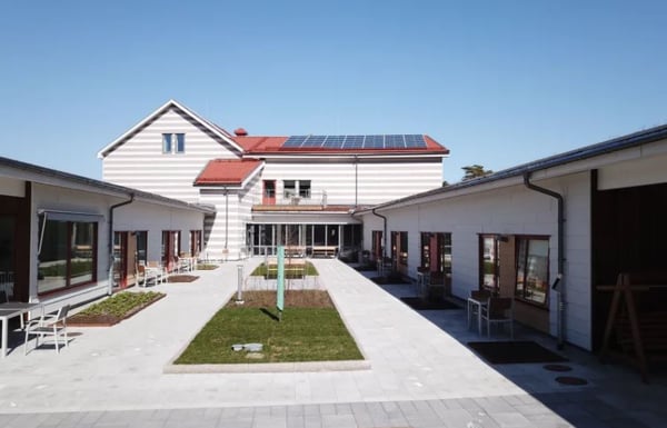 Lägenhetsområde med vita byggnader, innergård och tak med solpaneler