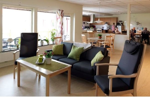 Vardagsrum och kök med ljusa möbler, soffa, fåtöljer och matplats