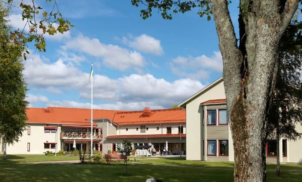 Lägenhet i flerbostadshus med röda tak, gräsmatta och flaggstång