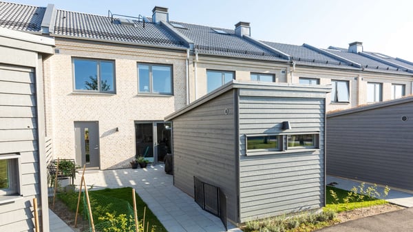 Inflyttningsklar lägenhet med grå träfasad och liten uteplats