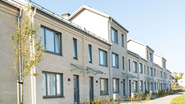 Rad av moderna radhus med ljus putsfasad och stora fönster