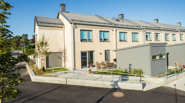 Inflyttningsklar lägenheter med radhusfasad, uteplats och små grå förråd