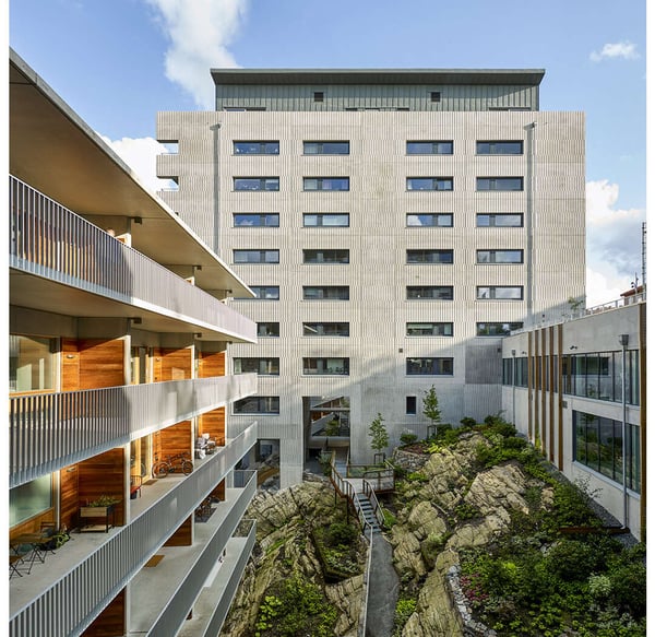 Innergård med moderna bostadshus, balkonger och en grönskande bergsmiljö