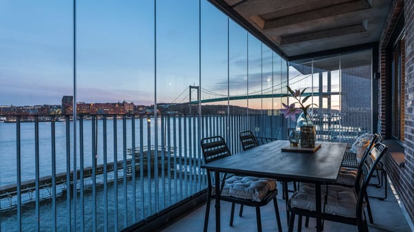 Uteplats med utsikt över vatten, bro och stadssilhuett i skymning