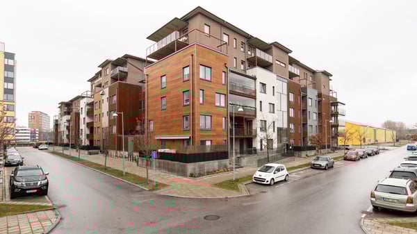 Bostadshus med moderna lägenheter och parkerade bilar längs en gata