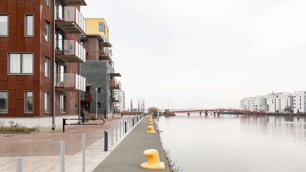 Bostadshus vid vatten med balkonger och gångväg längs kajen