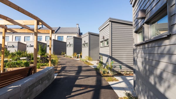 Hus med grå fasader och en asfalterad gångväg i bostadsområdet