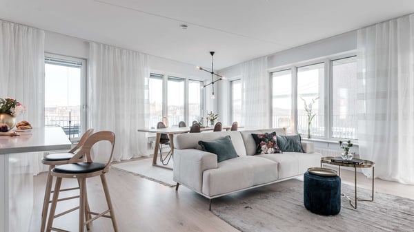 Inflyttningsklar lägenhet med ljus, öppen planlösning, stora fönster och vit soffa
