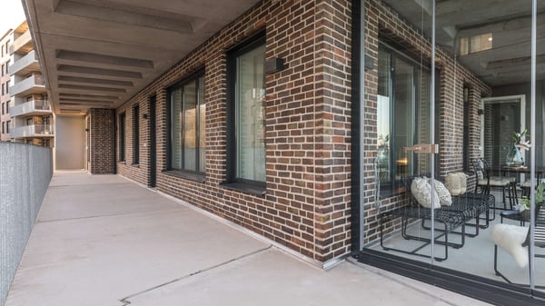 Balkong och fasad i tegel med stora glaspartier i ett modernt flerbostadshus