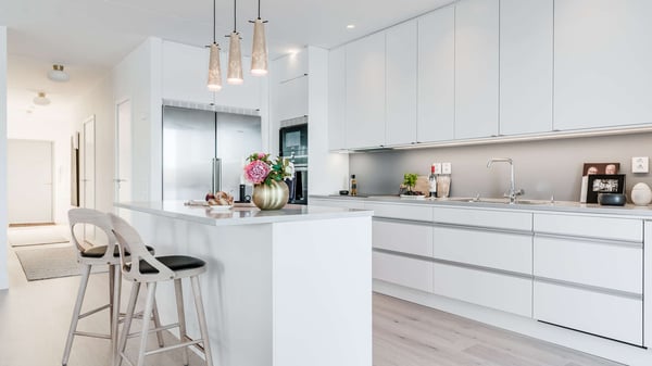 Lägenhet med modernt vitt kök, köksö och barstolar
