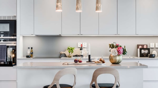 Lägenhet med modernt vitt kök, köksö och ljusa barstolar