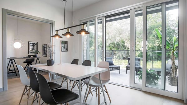Inflyttningsklar lägenhet med modern matsal, stora glaspartier och utgång till uteplats