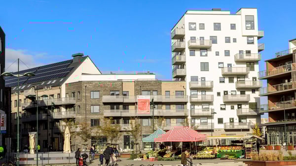 Urbant bostadskvarter med flerfamiljshus, balkonger och en torgyta med marknadsstånd framför