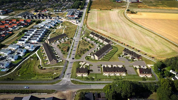 Flygvy över ett bostadsområde med radhus, flerbostadshus och åkermark