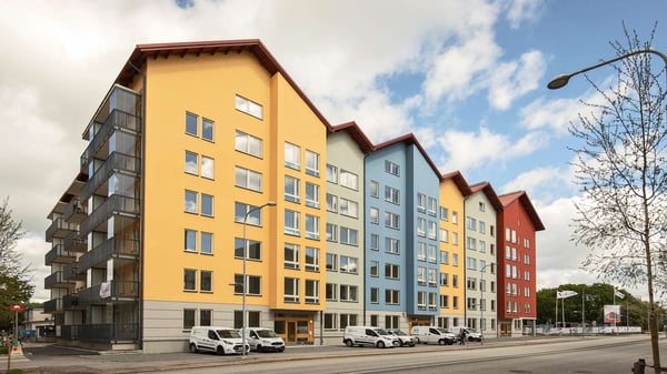 Flerbostadshus i färgglada fasader med balkonger och parkerade bilar utanför