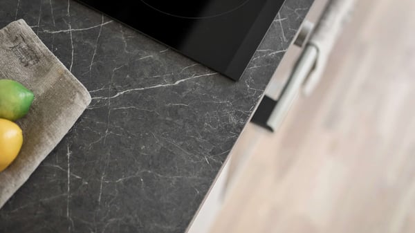 Närbild av ett kök med mörk marmormönstrad bänkskiva och fruktskål