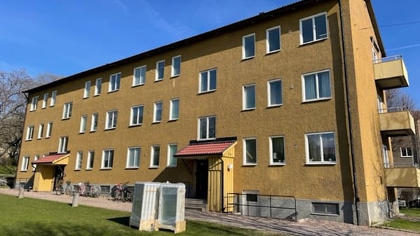 Flerbostadshus i gul fasad med flera fönster och balkonger