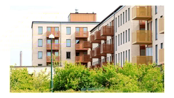 Flerbostadshus med balkonger och grönska framför