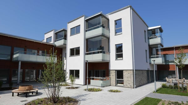 Modern flerbostadshus med balkonger och innergård i dagsljus