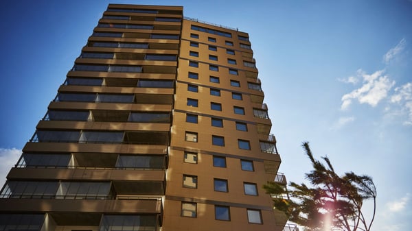 Hög bostadsbyggnad med balkonger mot blå himmel