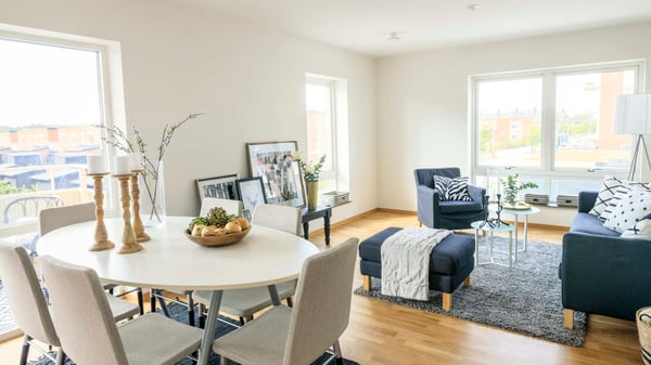 Inflyttningsklar lägenhet med ljus öppen planlösning, matplats och vardagsrum med soffa, fåtölj och stora fönster