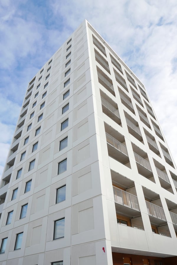 Exteriör av ett vitt höghus med balkonger och fönster mot en blå himmel