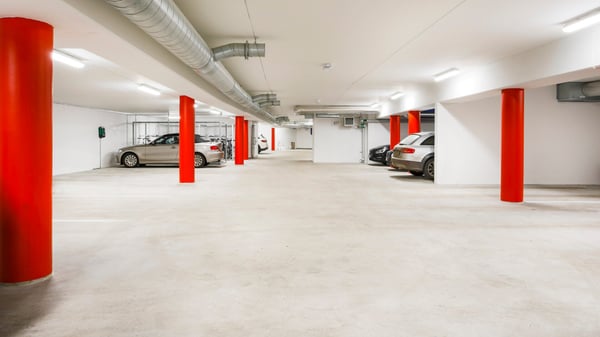 Underjordiskt garage med röda pelare och parkerade bilar