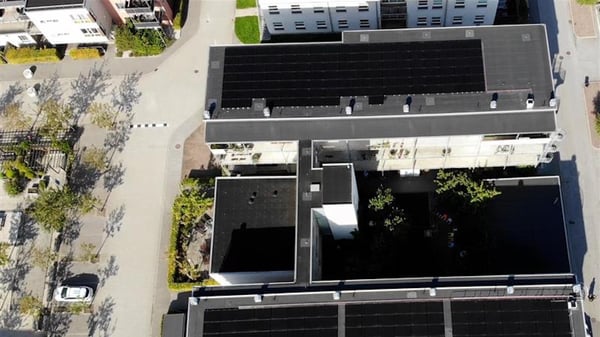 Flygfoto över ett bostadshus med svarta tak och innergård