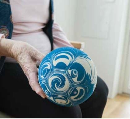 En person håller i en blå och vit keramisk boll med virvlande mönster