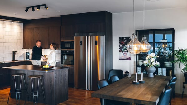 Personer i ett modernt kök och matsal med mörka trädetaljer