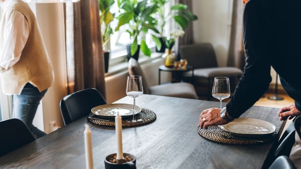 Personer som dukar ett matbord i en ljus bostad
