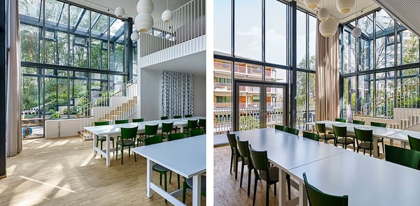 Gemensamhetslokal med ljusa, öppna ytor, stora fönster och gröna stolar vid vita bord
